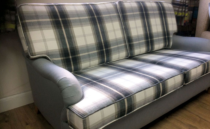A sofa re-upholstered in contemporary and contrasting check and plain fabrics